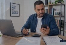 Pessoa analisando contrato, calculadora e orçamento para calcular saldo devedor antes da quitação antecipada.